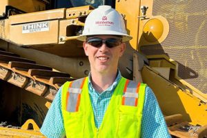 Ben Caldwell, Equipment Manager, in front of equipment wearing PPE.