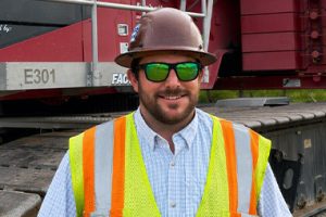 Dylan Foster wearing PPE in front of a crane.